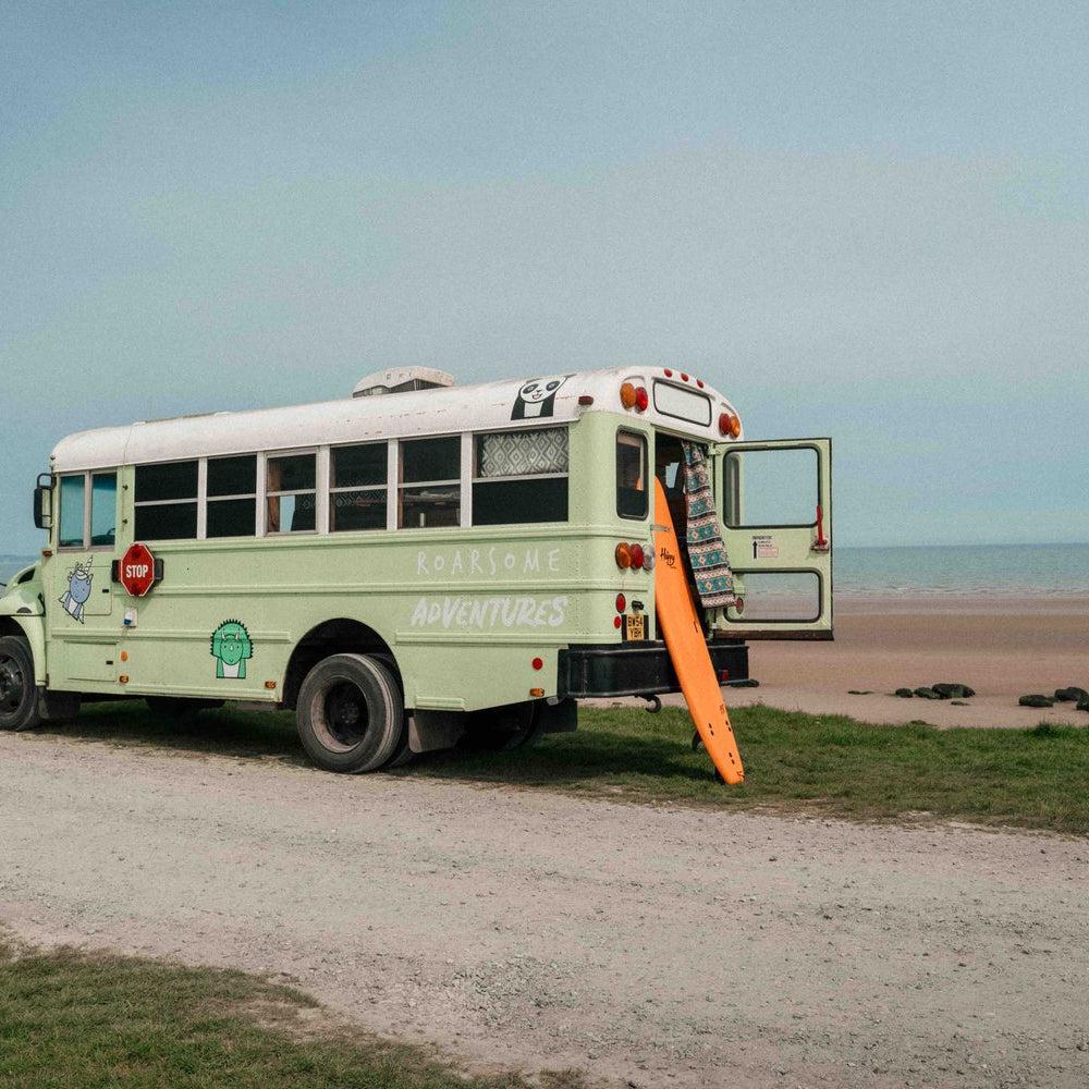 Adventure bus parked beside a sandy beach
