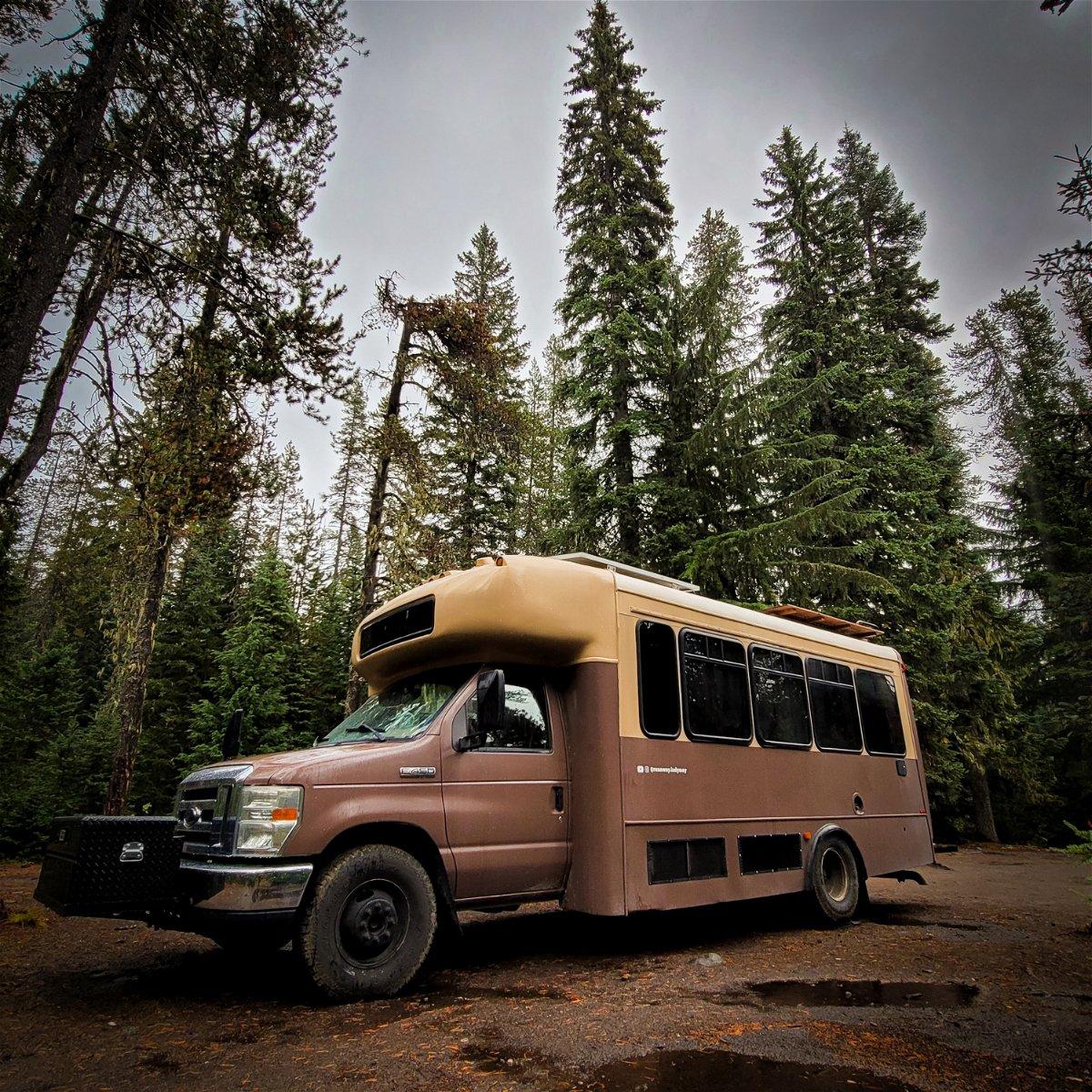 Off-grid bus parked beside forest