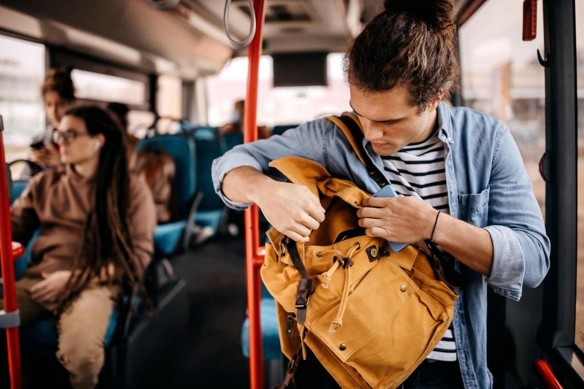 Traveler securing backpack on bus