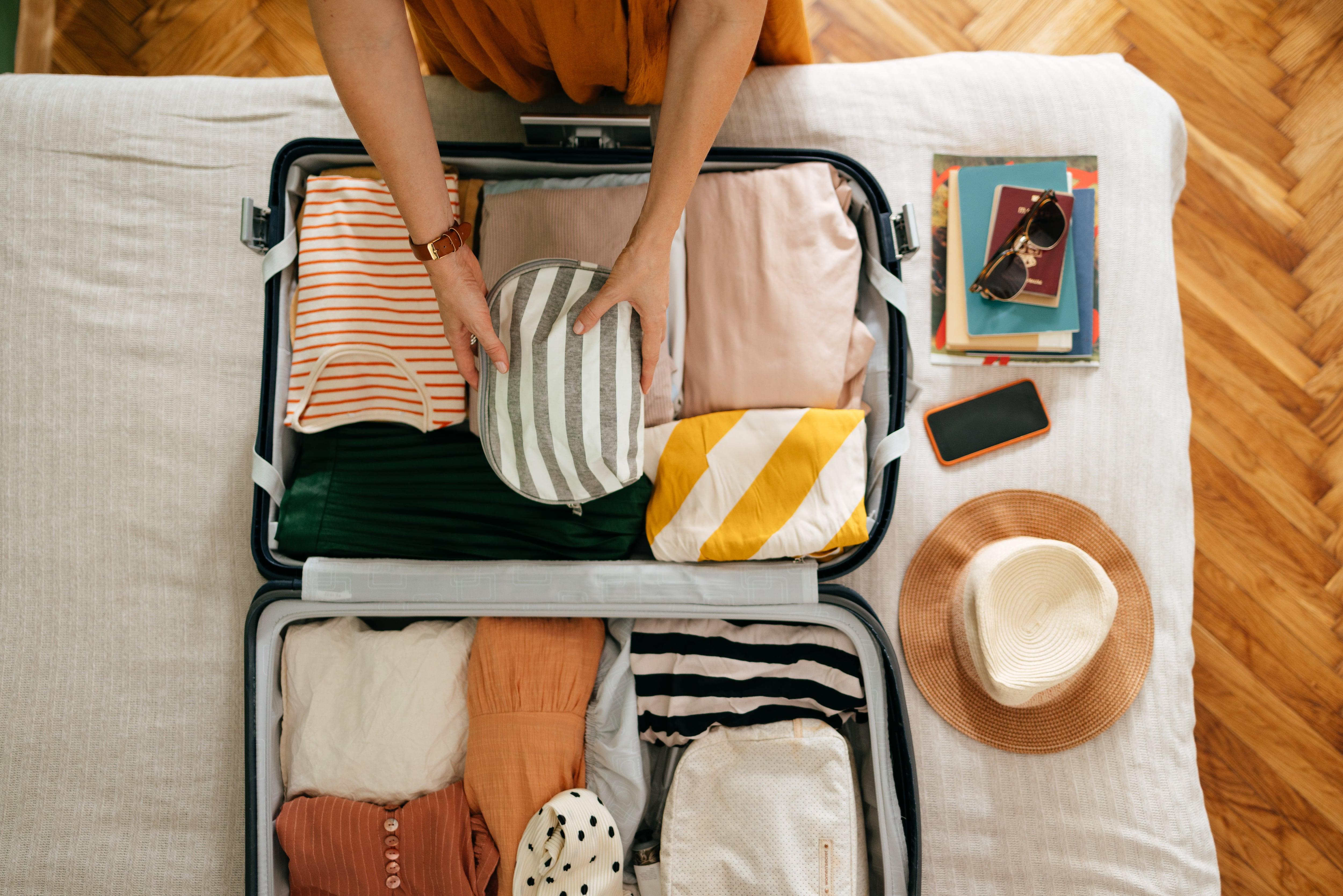 Travel suitcase packed with outfit bundles using a clothes folding trick method